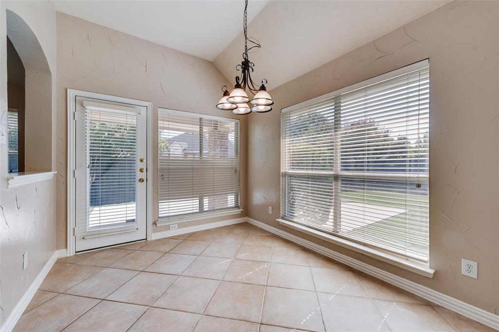 Vaulted ceiling with an iron chandelier, large windows with horizontal blinds, diagonal ceramic tile flooring, and a glass-paneled exterior door