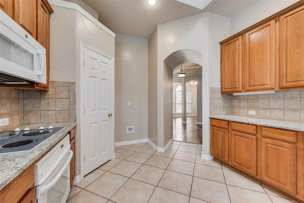 Kitchen featuring wood cabinetry, stone countertops, square tile backsplash, built-in electric cooktop with over-the-range microwave, and ceramic tile flooring