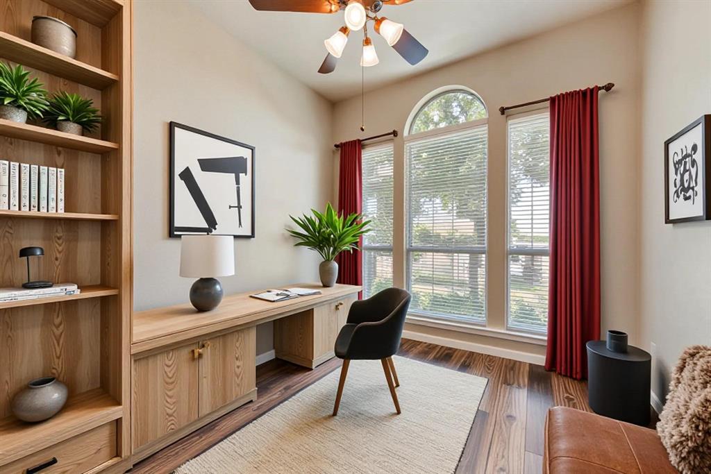 Built-in wood cabinetry, expansive wood-finish flooring, ceiling fan, and large windows featuring an arched transom