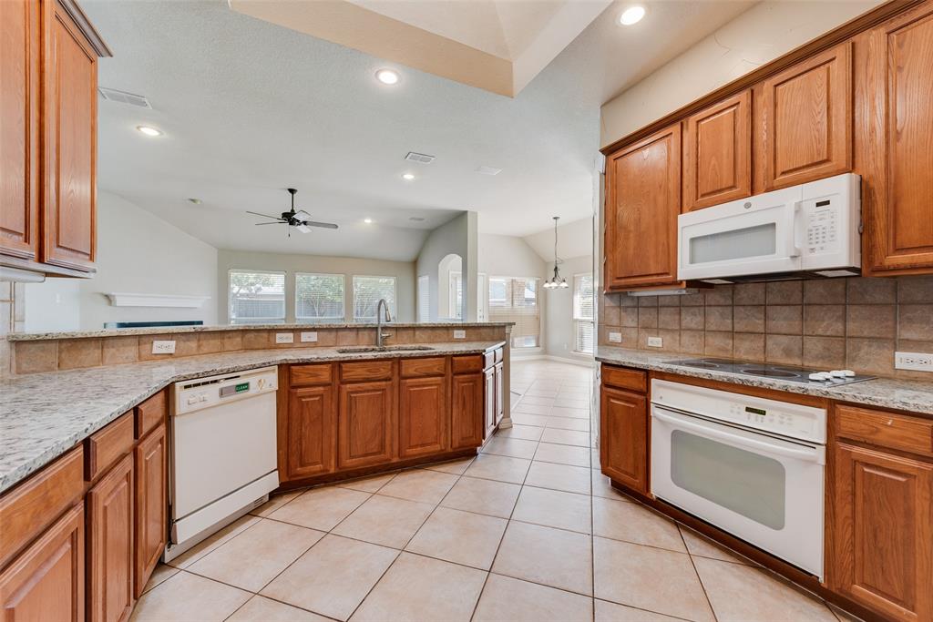 Kitchen featuring wood cabinetry, stone countertops, square tile backsplash, tile flooring, and recessed lighting