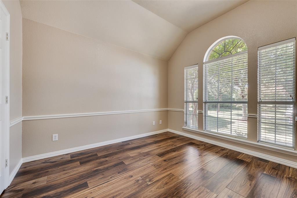 Vaulted ceiling featuring an arched window, wood-finish flooring, and chair rail molding