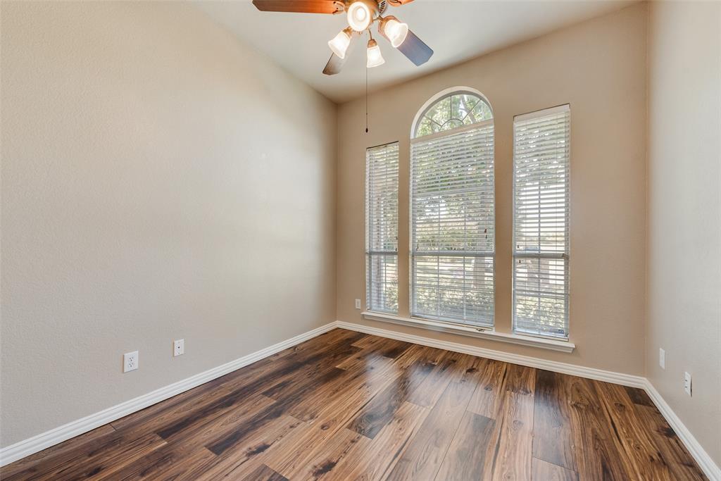 High ceilings featuring an arched window configuration, wood-finish flooring, and a multi-bulb ceiling fan with integrated lighting