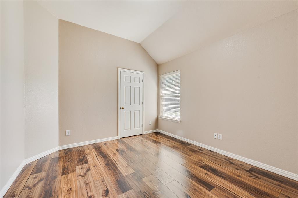 Vaulted ceilings, wood-finish flooring, six-panel interior door, and window with integrated blinds