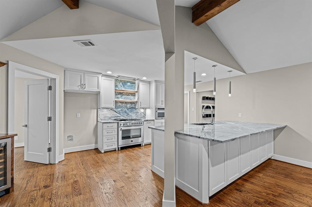 The open kitchen features white cabinetry and a high-end stainless steel gas range