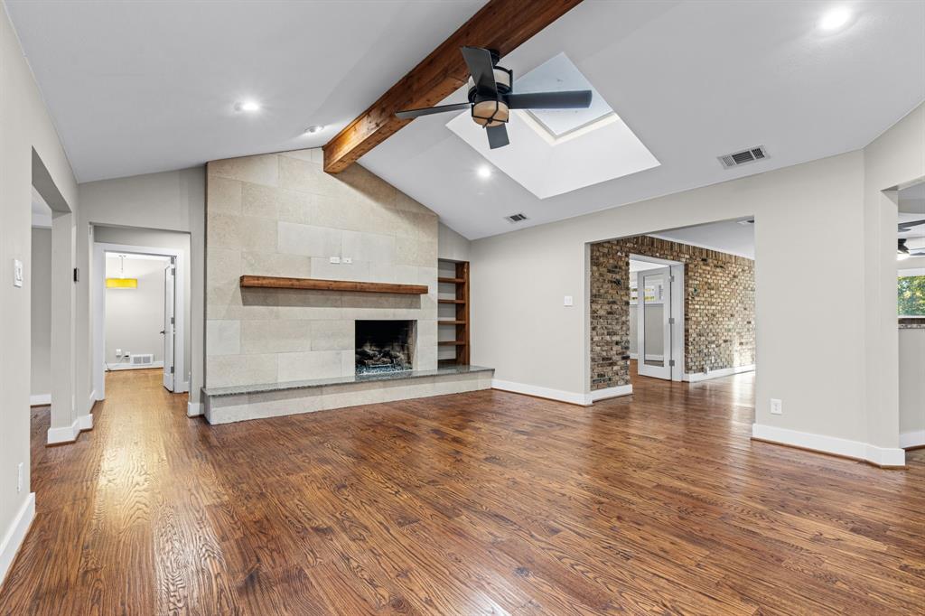 Vaulted ceiling with exposed wood beam, stone-surround fireplace with wood mantel and a skylight Vaulted ceiling with exposed wood beam, stone-surround fireplace with wood mantel and a skylight