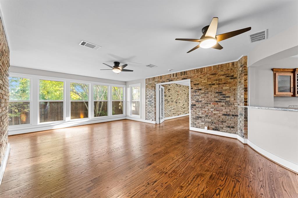 The second living area featuring exposed brick walls, windows to the backyard and dual ceiling fans