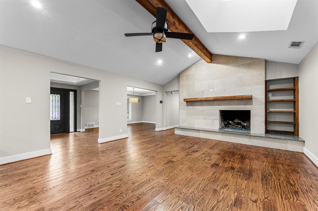 Vaulted ceiling featuring a prominent wooden beam, stone fireplace with a wooden mantel and built-in shelving Vaulted ceiling featuring a prominent wooden beam, stone fireplace with a wooden mantel and built-in shelving