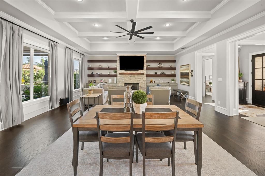 Coffered ceiling with recessed lighting, stone fireplace, custom wood-finish floating shelves, and dark wood-finish flooring