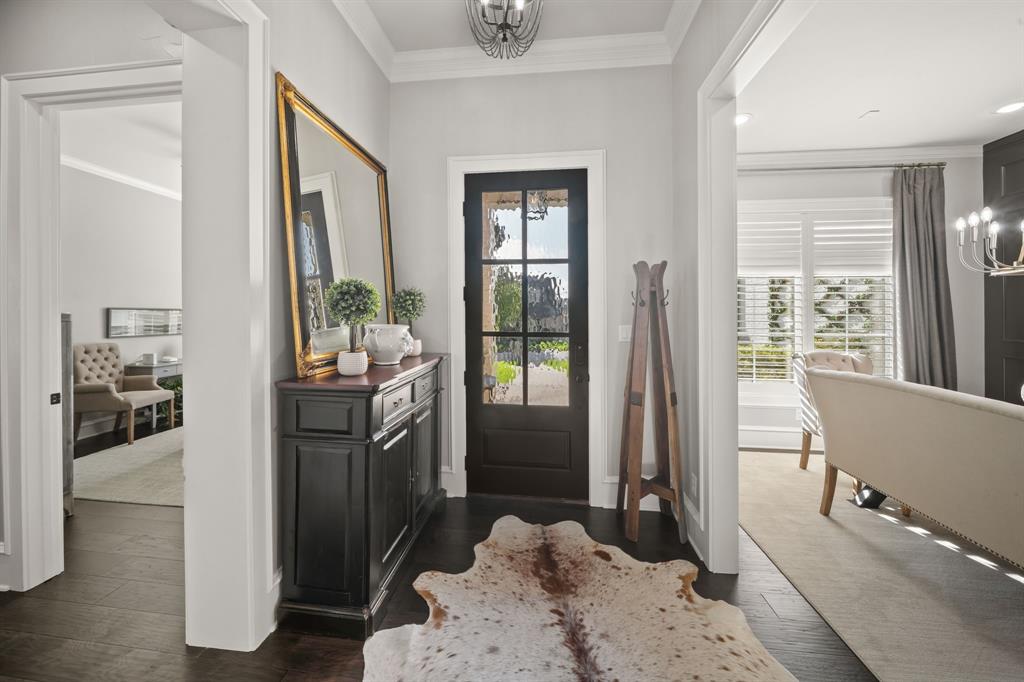 Entryway featuring dark-stained wood flooring, a multi-pane glass door, crown molding, and a decorative ceiling fixture