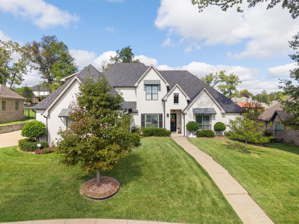 Stucco exterior featuring multi-gabled rooflines, black metal awnings, grid-pattern windows, and a paved walkway