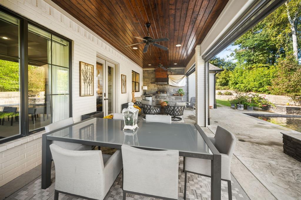 Covered patio featuring a stained wood plank ceiling, recessed lighting, brick exterior walls, and an outdoor kitchen with stone masonry finishes Covered patio featuring a stained wood plank ceiling, recessed lighting, brick exterior walls, and an outdoor kitchen with stone masonry finishes