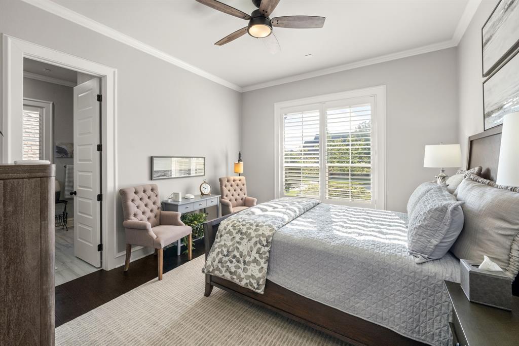 Room featuring dark wood-finish flooring, white plantation shutters, crown molding, and a multi-blade ceiling fan with integrated lighting