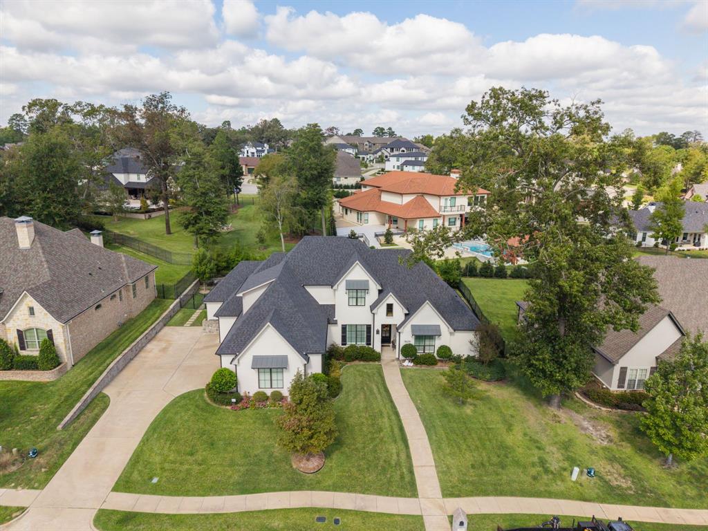 Multi-gabled roofline with shingled exterior, light-toned masonry facade, decorative metal window awnings, and multi-car concrete driveway