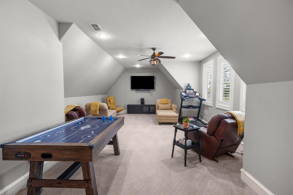 Expansive room featuring vaulted ceilings, neutral wall-to-wall carpeting, recessed lighting, a ceiling fan with integrated light fixture, and plantation shutters
