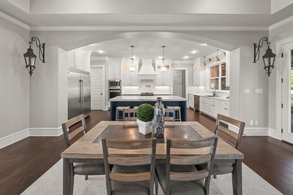 Kitchen area featuring an oversized central island with a contrasting base, white shaker-style cabinetry, stainless steel appliances, recessed ceiling lighting, and dark wood-finish flooring