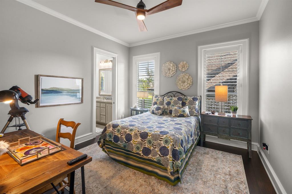 Bedroom featuring dark wood-finish flooring, ceiling fan, and windows equipped with plantation shutters