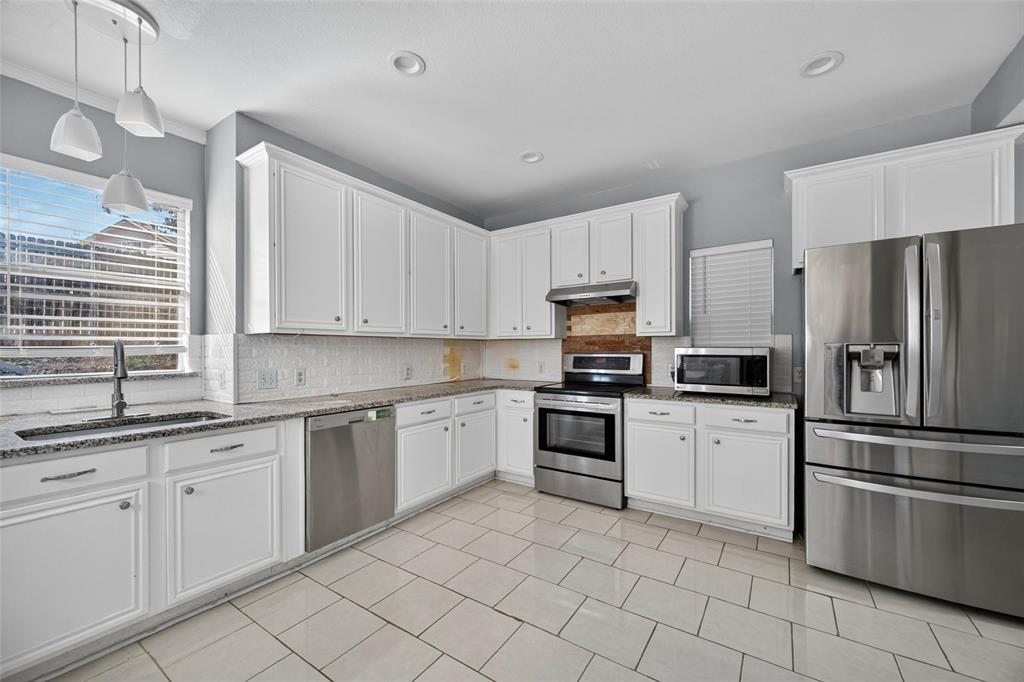 Kitchen featuring white shaker-style cabinetry, stone countertops, stainless steel appliances, tile flooring, and recessed lighting