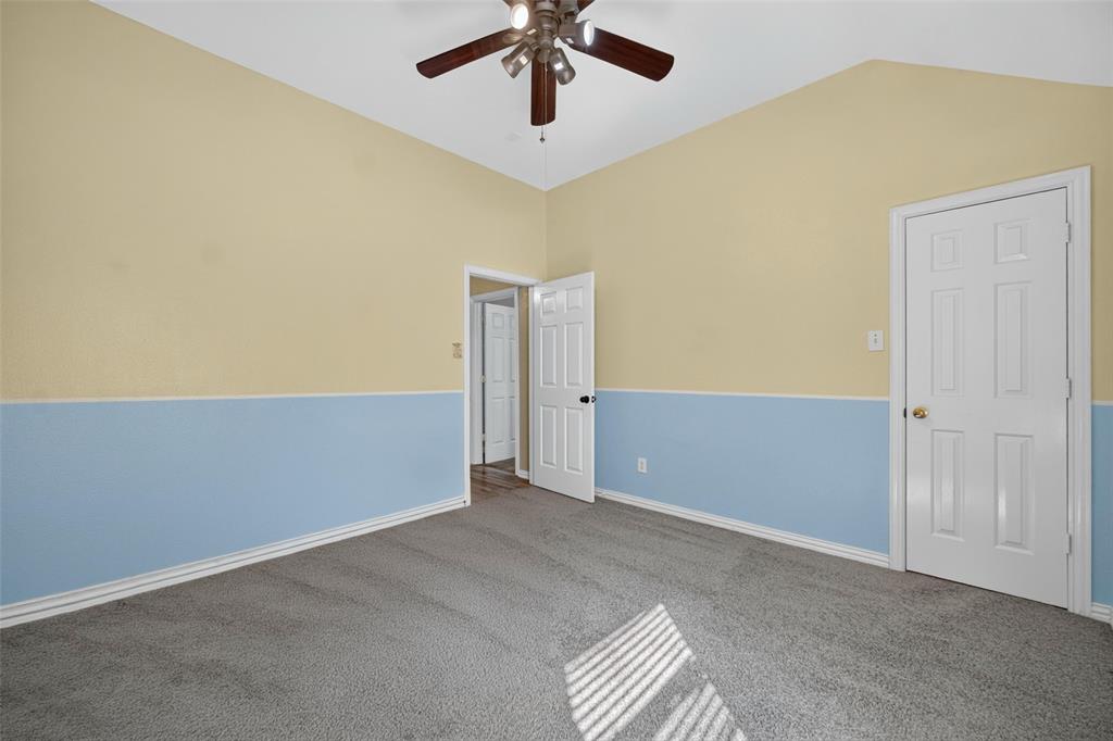 Vaulted ceilings featuring a multi-blade ceiling fan, neutral wall-to-wall carpeting, and six-panel interior doors