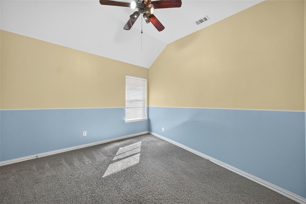 Vaulted ceiling room featuring neutral carpeting, a central multi-blade ceiling fan, and a single window with horizontal blinds