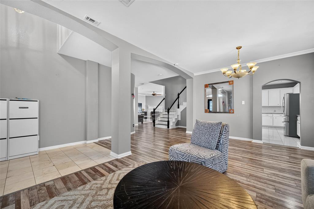Open-concept interior featuring wood-finish flooring, tile accent flooring, archway architectural detailing, and a multi-arm chandelier
