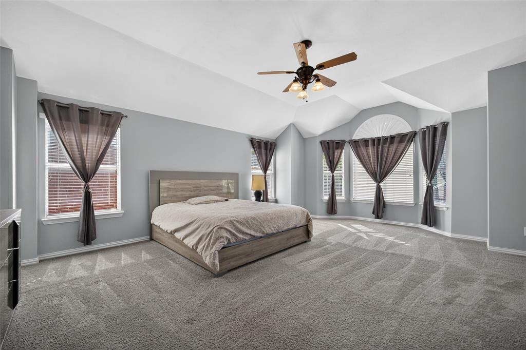 Vaulted ceilings with a ceiling fan, neutral wall paint, and windows featuring an arched top accent