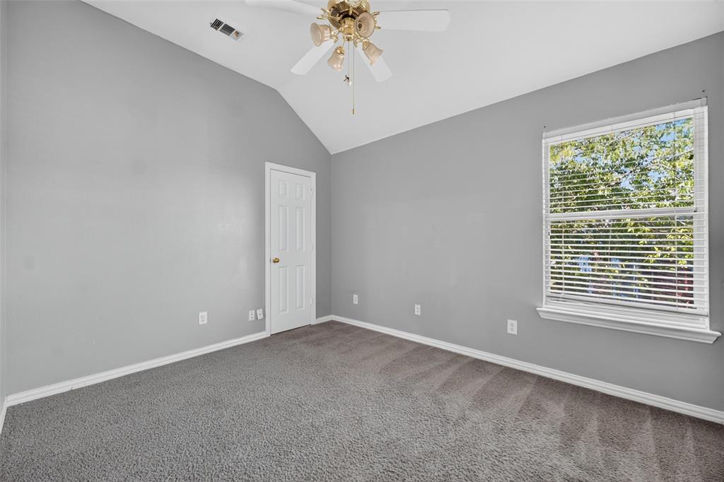 Vaulted ceilings, neutral wall tones, neutral carpeting, multi-pane window with blinds, and ceiling fan fixture