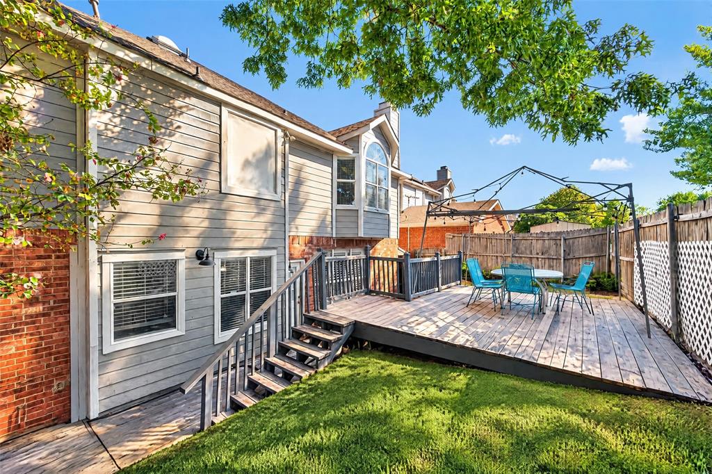 Exterior featuring a raised wood deck, metal-frame gazebo, brick and siding facade, and a fenced backyard