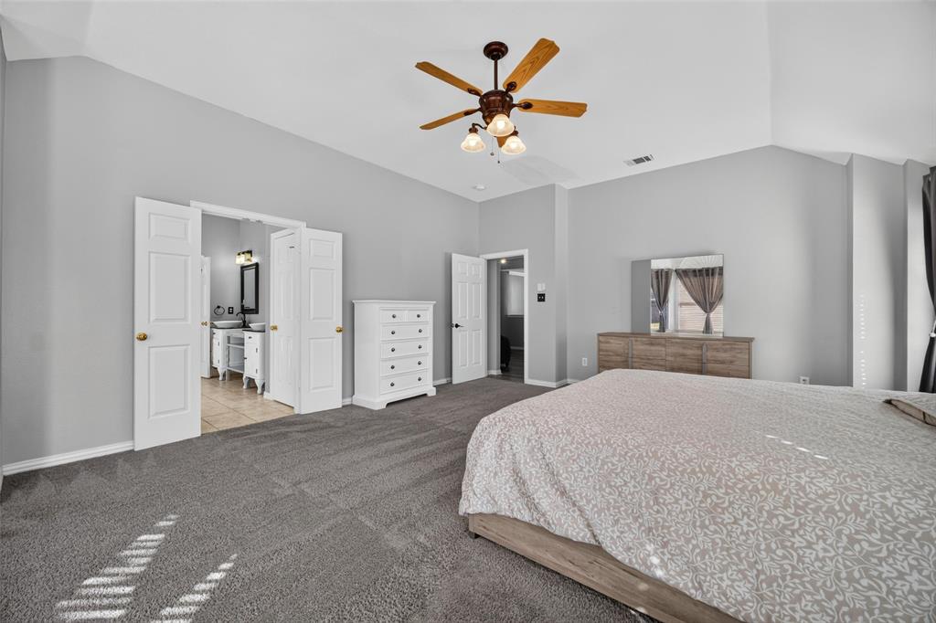 Vaulted ceilings, neutral wall tones, carpeted flooring, and a central ceiling fan with integrated lighting