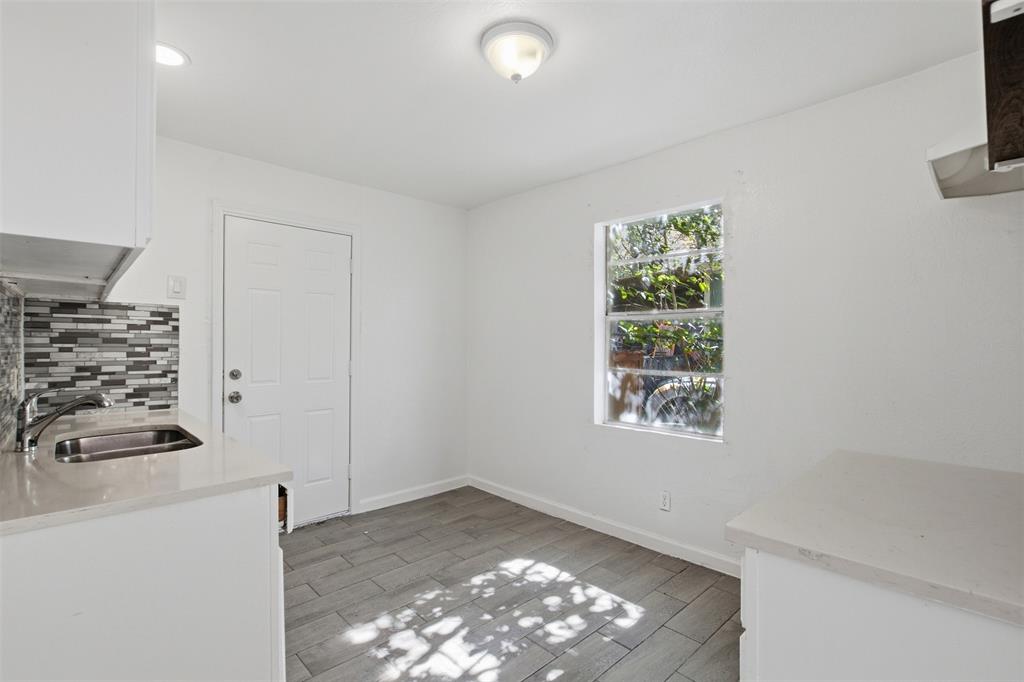Kitchen space featuring tile flooring, quartz countertops, a stainless steel undermount sink, a multi-tone tile backsplash, and a single-hung window