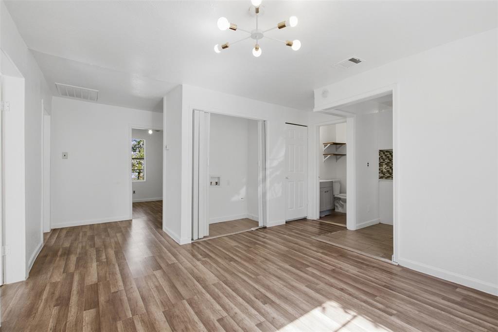 Wood-finish flooring, modern multi-arm light fixture, and dedicated laundry area with bifold doors