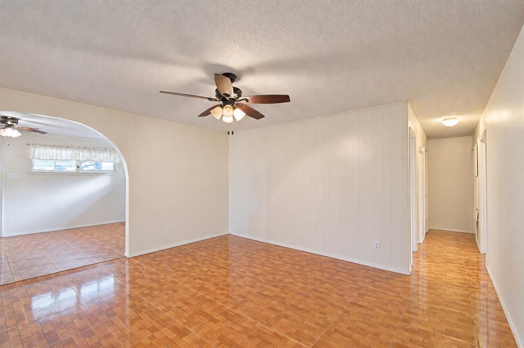 Interior space featuring an arched entryway, tile flooring, and a ceiling fan with integrated lighting