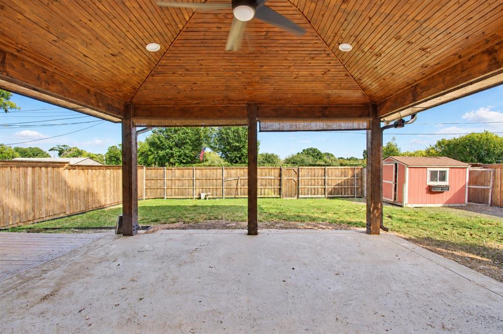 Covered patio featuring a wood-planked vaulted ceiling, recessed lighting, ceiling fan, and concrete flooring, bounded by a wood privacy fence