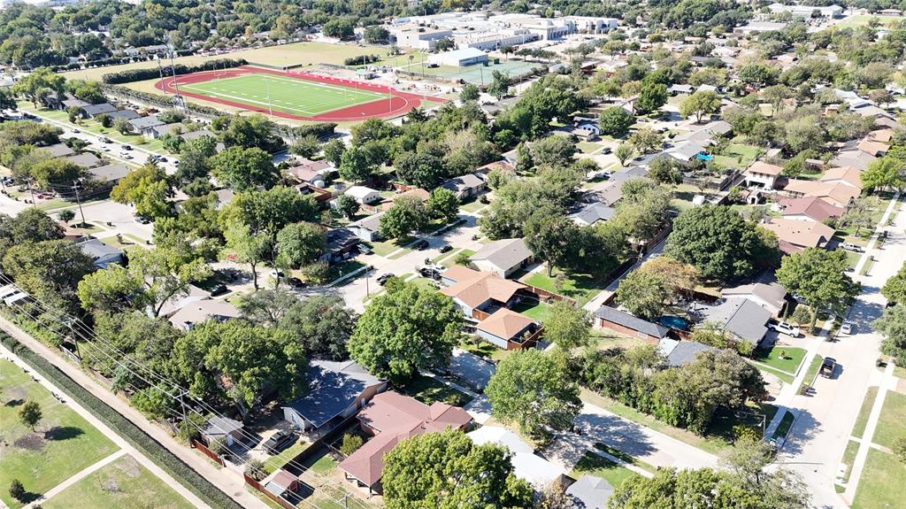 Aerial perspective of a residential neighborhood featuring mature canopy trees, established landscaping, and proximity to athletic fields and track facilities