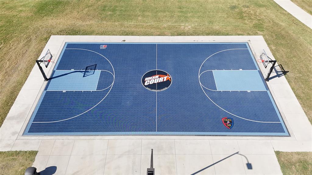 Outdoor basketball court with a specialized synthetic surface, dual adjustable-height goal systems, concrete perimeter, and painted boundary markings