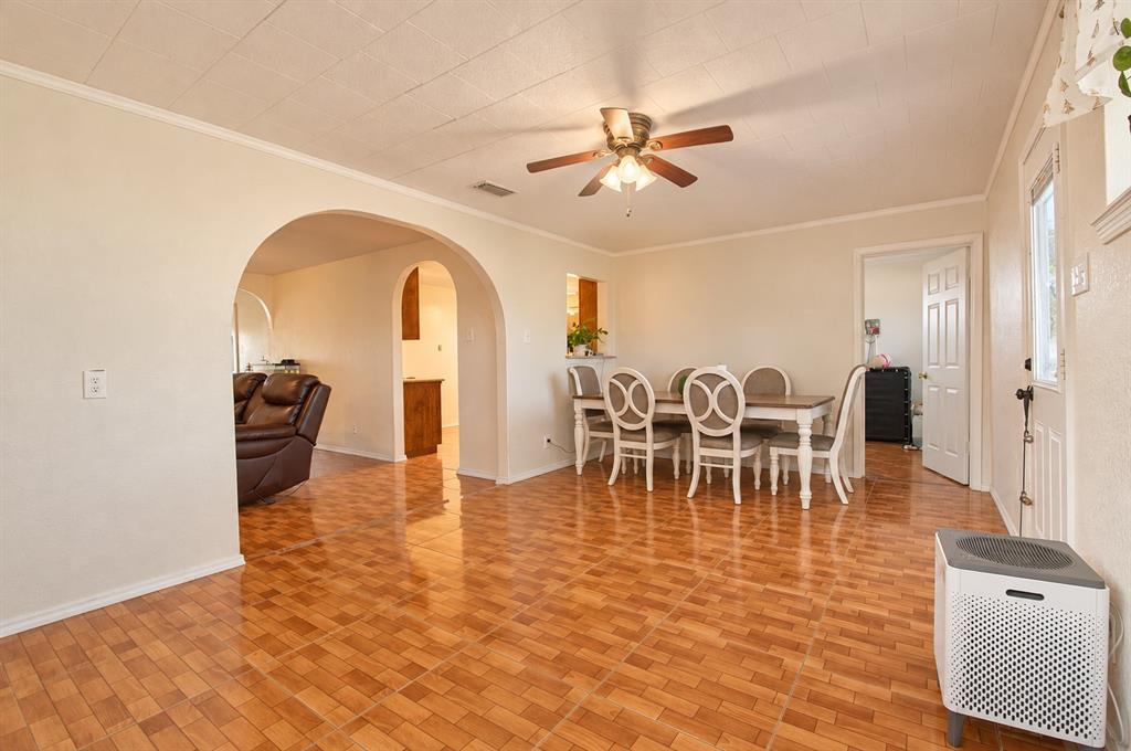 Open living area featuring ceramic tile flooring, distinctive arched doorways, a ceiling fan with light fixture, and a pass-through opening