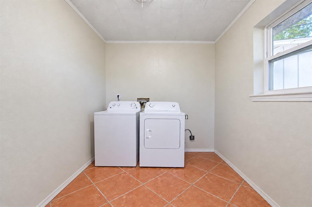 Utility room featuring terracotta-style ceramic tile flooring, neutral wall finishes, and a single-pane window