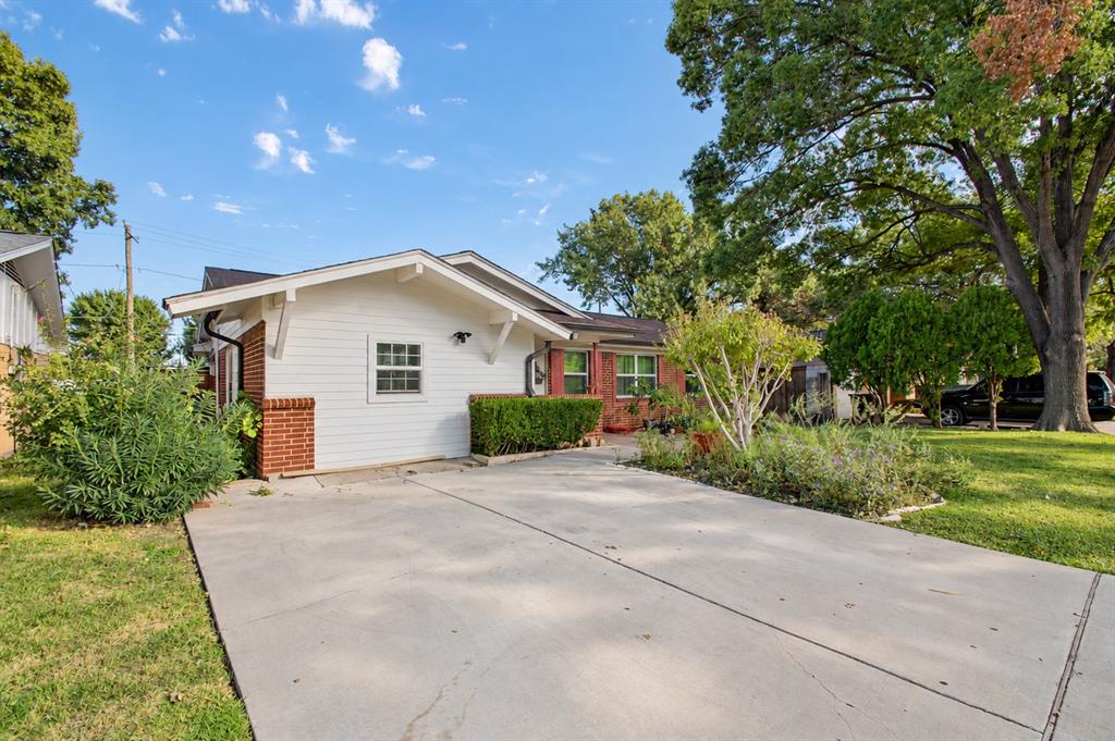 Exterior facade featuring white horizontal siding, red brick accents, and a concrete driveway