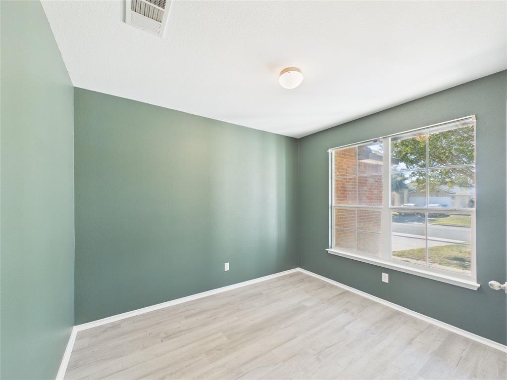 Downstairs Office featuring light wood-finish flooring, dual-pane window with muntins, and a flush-mount ceiling light fixture Downstairs Office featuring light wood-finish flooring, dual-pane window with muntins, and a flush-mount ceiling light fixture
