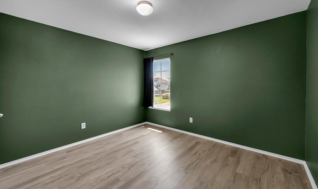 Upstairs Bedroom featuring wood-finish flooring, high-contrast dark green walls, a single-pane window with a muntin grid, and a ceiling-mounted light fixture