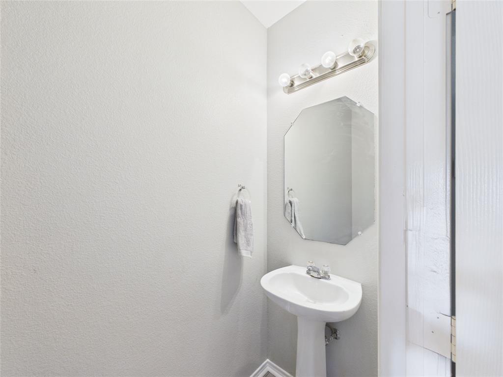 HALF BATH down stairs Pedestal sink with a dual-handle faucet, octagonal wall mirror, and four-bulb vanity lighting fixture