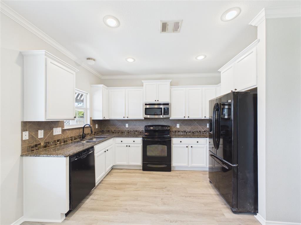Kitchen featuring white cabinetry, stone-finish countertops, tiled backsplash, black built-in appliances, and wood-finish flooring Kitchen featuring white cabinetry, stone-finish countertops, tiled backsplash, black built-in appliances, and wood-finish flooring