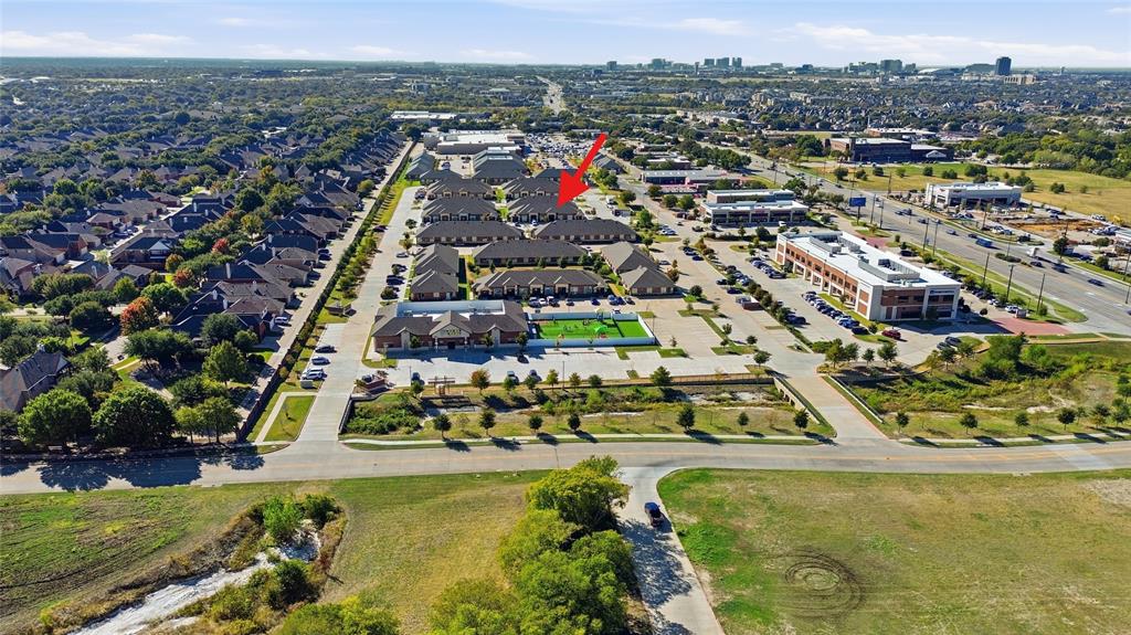 Aerial perspective of a multi-unit property complex featuring pitched shingle roofing, brick and stone masonry facades, and paved parking surfaces Aerial perspective of a multi-unit property complex featuring pitched shingle roofing, brick and stone masonry facades, and paved parking surfaces