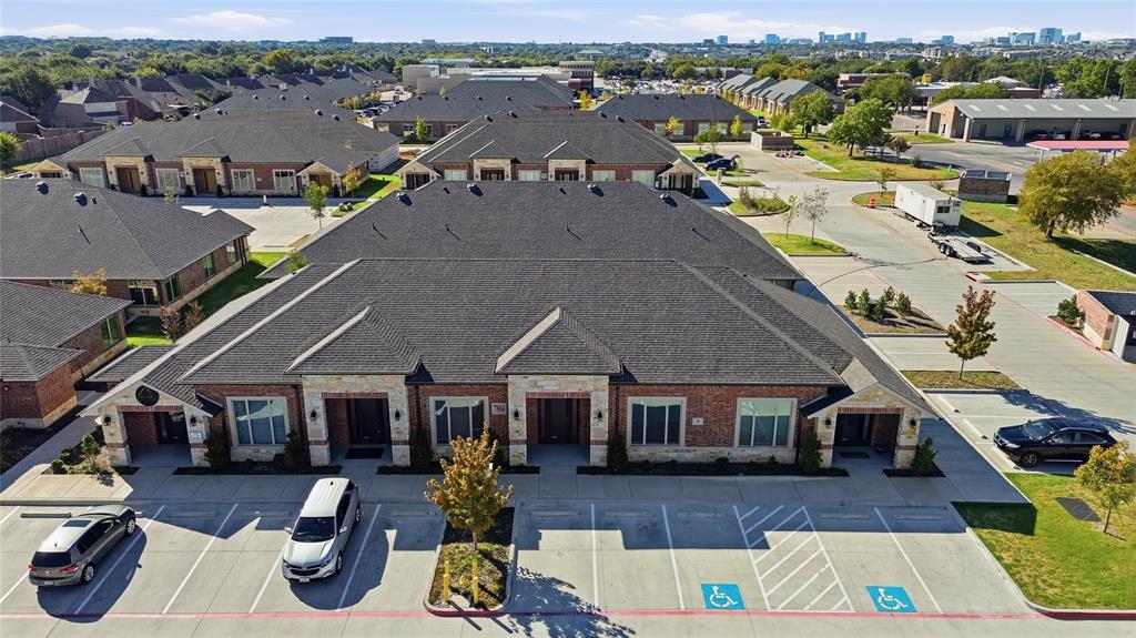 Brick and masonry exterior featuring shingle roofing, paved surface parking, and exterior lighting fixtures Brick and masonry exterior featuring shingle roofing, paved surface parking, and exterior lighting fixtures