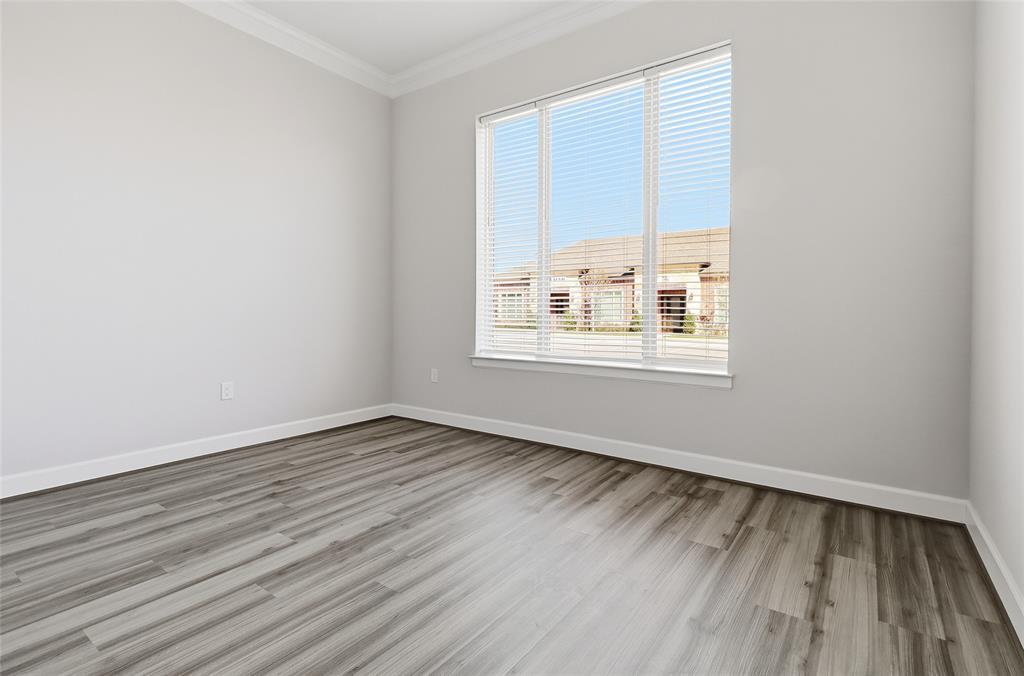 Neutral-toned interior space featuring wood-finish flooring, crown molding, and a multi-panel window Neutral-toned interior space featuring wood-finish flooring, crown molding, and a multi-panel window
