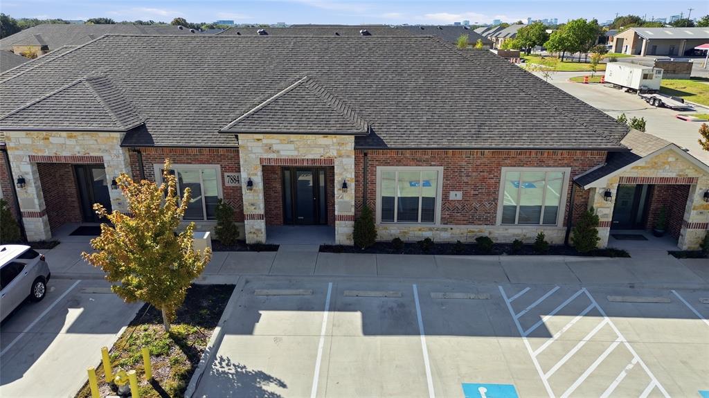 Multi-tenant building featuring brick and stone masonry, multi-gabled roofline, concrete parking area, and manicured foundation landscaping Multi-tenant building featuring brick and stone masonry, multi-gabled roofline, concrete parking area, and manicured foundation landscaping