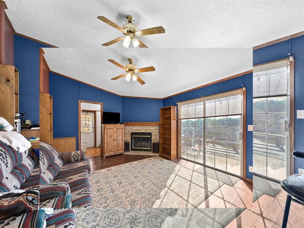 Living area featuring a stone-surround fireplace, built-in shelving, sliding glass doors, and a ceiling fan with integrated lighting