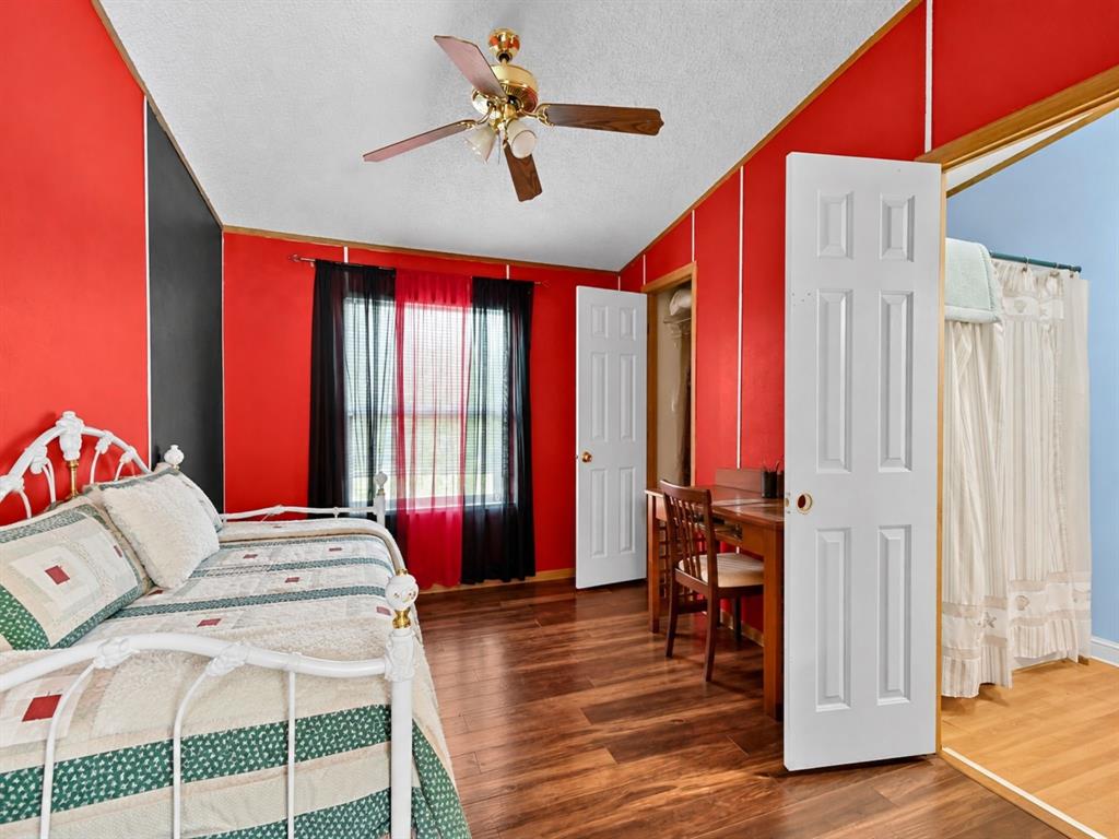 Wood-finish flooring, brass-finish ceiling fan with integrated lighting, and multiple interior six-panel doors