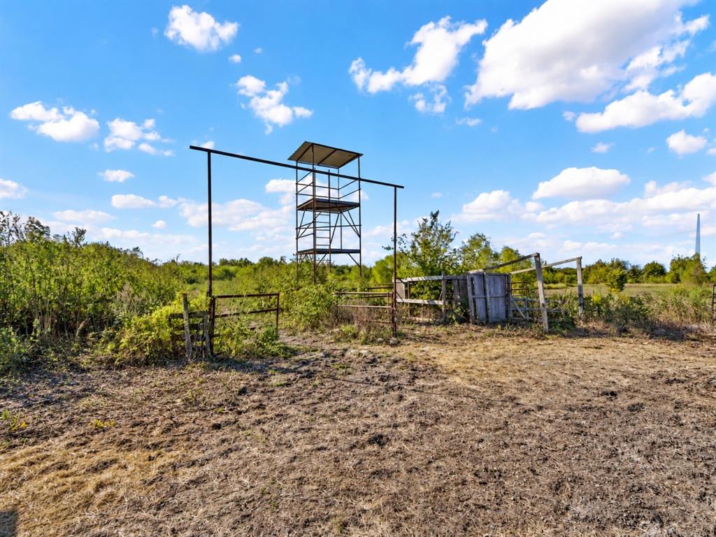 Expansive land featuring a metal observation tower, metal perimeter fencing, and rural vegetation