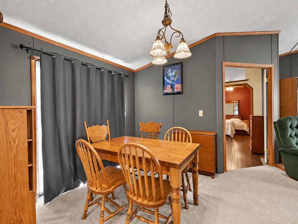 Dining area featuring neutral carpeting, a multi-light chandelier, wood-finish trim, and sliding glass doors