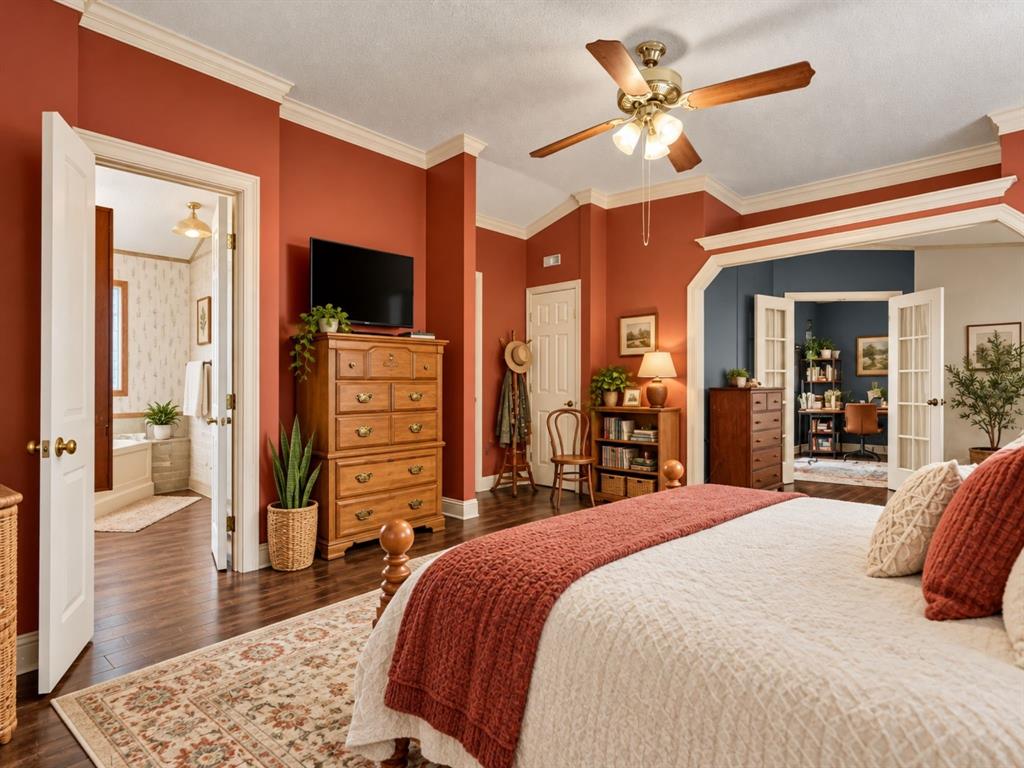 Wood-finish flooring, vaulted ceiling, crown molding, ceiling fan with integrated lighting, and French doors